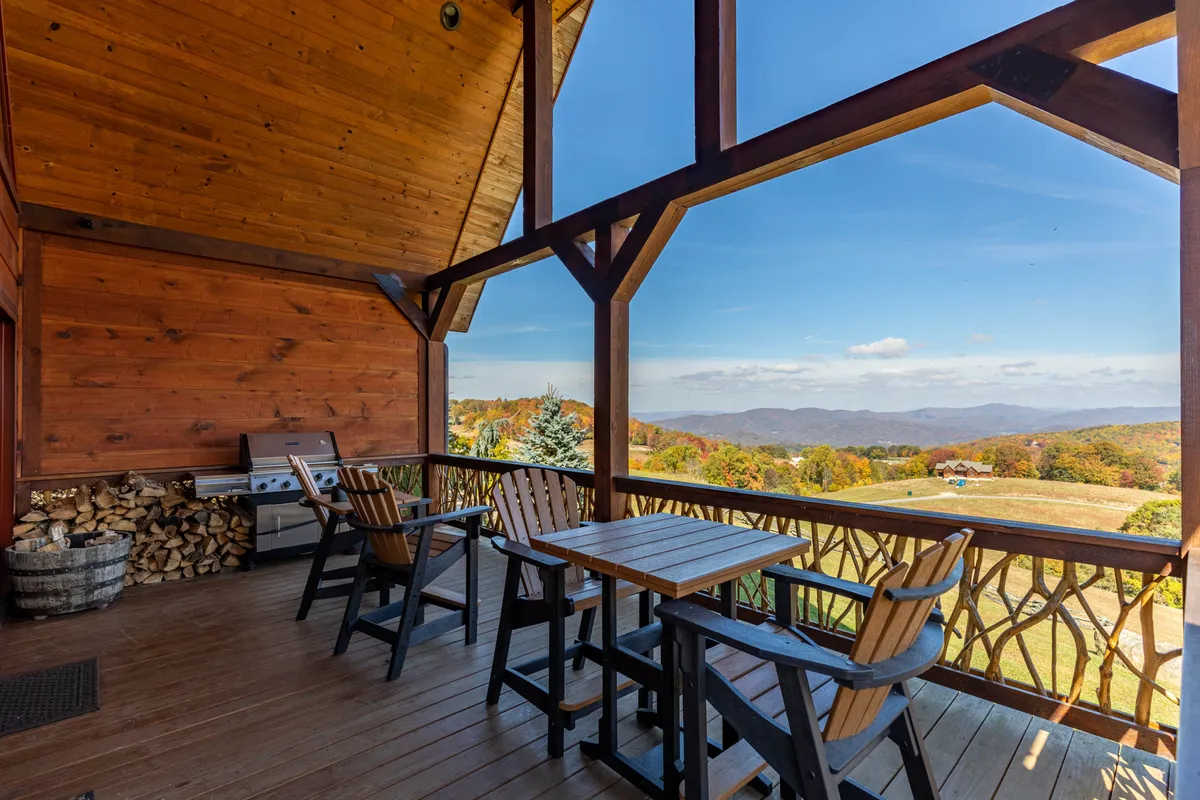 This image features a spacious wooden deck equipped with comfortable outdoor seating and a grill area, set against a breathtaking backdrop of mountains. The deck offers plenty of space for relaxing, dining, and taking in the tranquil surroundings. Early morning and evening light highlight the deck’s inviting ambiance, and the view extends to the scenic High Country landscape.